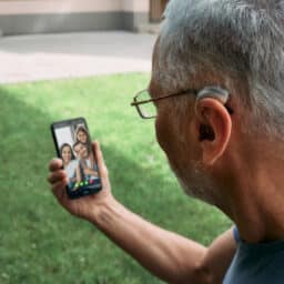 Man with hearing aid video chatting with his family.