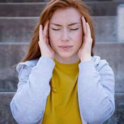 Woman experiencing tinnitus holding her head.