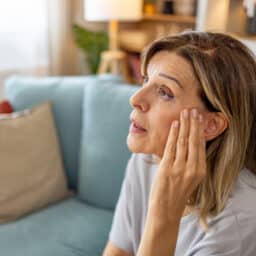 Woman rubbing her temples experiencing tinnitus