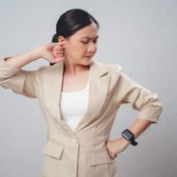 Woman in suit holds ear
